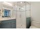 Bathroom featuring a glass shower, blue vanity, bright lighting, and tiled walls and floors at 7922 Sailboat Key S Blvd # 105, South Pasadena, FL 33707