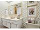 Bathroom featuring golden wallpaper, dual mirrors, a bright sink, and decorative accents at 805 Bannockburn Ave, Temple Terrace, FL 33617