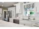 Beautiful kitchen features white cabinets, marble countertops, stainless steel appliances, and a window with patterned shade at 805 Bannockburn Ave, Temple Terrace, FL 33617