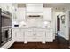 An elegant white kitchen features updated appliances, a patterned backsplash, and dark wood floors at 805 Bannockburn Ave, Temple Terrace, FL 33617