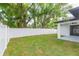 Fenced backyard showcasing green grass, mature trees, and a covered patio, providing privacy and outdoor enjoyment at 907 E Okaloosa Ave, Tampa, FL 33604