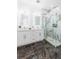 Modern bathroom with double vanity, illuminated mirrors, and frameless glass shower with marble-look tile at 907 E Okaloosa Ave, Tampa, FL 33604