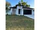 Modern home featuring black garage door, stylish white facade, and freshly cut lawn at 907 E Okaloosa Ave, Tampa, FL 33604