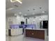 Bright kitchen featuring white cabinetry, gold hardware, marble backsplash, and kitchen island at 907 E Okaloosa Ave, Tampa, FL 33604