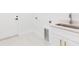 Laundry area with white cabinets, sink, quartz countertop and white floor tiles at 907 E Okaloosa Ave, Tampa, FL 33604