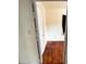 View into the bedroom featuring hardwood floors, neutral walls, and a door in need of repair at 10803 N Florence Ave, Tampa, FL 33612
