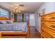 Bright bedroom featuring wood floors, ceiling fan, and dresser with paneled wood door at 12303 Fieldstone Ln, Hudson, FL 34667