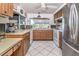 Bright kitchen featuring stainless steel refrigerator, white appliances, wood cabinets and white tile floor at 12303 Fieldstone Ln, Hudson, FL 34667