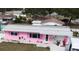Single story home, painted pink, with white trim, landscaping, and grey roof in a quiet neighborhood at 12425 Ridge Rd, Largo, FL 33778
