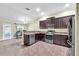 Kitchen with stainless steel appliances, dark brown cabinets, tile floor and view to the office space at 14233 Edinburgh Moor Dr, Wimauma, FL 33598