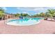 Large community pool with gradual entry, brick patio, palm trees, and umbrellas for shade on a sunny day at 14233 Edinburgh Moor Dr, Wimauma, FL 33598