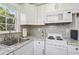 This kitchen features white cabinets, a tile backsplash, a stainless steel sink, and modern appliances at 157 9Th N Ave, St Petersburg, FL 33701