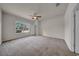 A carpeted bedroom featuring a ceiling fan and a large window for natural light and fresh air at 15810 Starling Water Dr, Lithia, FL 33547