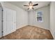 This carpeted bedroom features a ceiling fan and a window overlooking green trees at 15810 Starling Water Dr, Lithia, FL 33547
