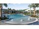 Resort-style pool showcasing a shallow entrance with fountains, surrounded by lounge chairs, and lush landscaping at 1738 Longliner Loop, Wesley Chapel, FL 33543