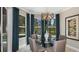 Dining area with a modern chandelier, glass table, four chairs, and views of the backyard at 1738 Longliner Loop, Wesley Chapel, FL 33543