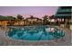 Beautifully lit lap pool at dusk, featuring clear water, lounge chairs, and nearby clubhouse and palm trees at 1738 Longliner Loop, Wesley Chapel, FL 33543