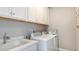 Well-lit laundry room with front load washer and dryer, ample cabinetry and gray walls at 1738 Longliner Loop, Wesley Chapel, FL 33543