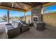 A covered outdoor patio with a stone fireplace and comfortable seating arrangement at 20417 Symphony Pl, Venice, FL 34293