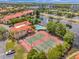 Aerial view of tennis courts and community pool beside lake near condos, highlighting a picturesque locale at 2400 Feather Sound Dr # 1136, Clearwater, FL 33762