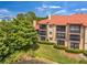 Exterior view showing several levels of screened patios, green lawn and nearby pond at 2400 Feather Sound Dr # 1136, Clearwater, FL 33762