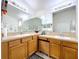Bathroom with dual sinks, wooden cabinets, and decorative mirrors at 24305 Denali Ct, Lutz, FL 33559