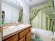 Traditional bathroom with a wooden vanity, green shower curtain, and neutral finishes at 24305 Denali Ct, Lutz, FL 33559