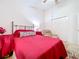 Bright bedroom with a red comforter on the bed, closet, and accent chair at 24305 Denali Ct, Lutz, FL 33559