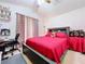 Comfortable bedroom featuring a red comforter, desk, and a ceiling fan at 24305 Denali Ct, Lutz, FL 33559