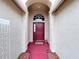 Covered front entryway featuring a red painted porch and decorative landscaping at 24305 Denali Ct, Lutz, FL 33559
