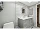 This bathroom features gray tiled walls, a gray vanity with a white countertop, and a matching framed mirror at 2701 W Osborne Ave, Tampa, FL 33614