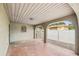 Covered carport area with arched supports, terracotta flooring, and view of fenced yard and neighboring buildings at 2701 W Osborne Ave, Tampa, FL 33614