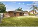 Exterior of a home with a fenced yard, mature trees, long driveway, and unique architectural design at 2701 W Osborne Ave, Tampa, FL 33614