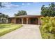 Charming single-story home with stucco exterior, arched entryway, mature landscaping, and long driveway at 2701 W Osborne Ave, Tampa, FL 33614