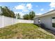 Green backyard featuring a modern gray house, white privacy fence, and lush greenery at 2906 E Columbus Dr, Tampa, FL 33605