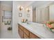 Bathroom vanity with wood cabinets, a wide mirror, and decorative wall sconces at 3416 W Morrison Ave, Tampa, FL 33629