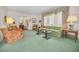 Spacious living room with vintage green carpet, large windows, and a view of the front yard at 3416 W Morrison Ave, Tampa, FL 33629