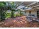 Charming brick patio under a pergola, furnished with a metal table and chairs, amidst lush landscaping at 3416 W Morrison Ave, Tampa, FL 33629