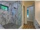 Stylish bathroom with marble-look shower and pebble floor, accented with dark fixtures and a window at 344 Bay St, Palm Harbor, FL 34683