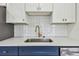 Modern kitchen sink features a gold faucet, white countertop and cabinets, and dark blue lower cabinets at 3535 16Th N St, St Petersburg, FL 33704