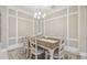 Elegant dining room with white chairs, wood table, decorative trim and chandelier at 4165 San Severo Rd, Wesley Chapel, FL 33543