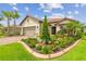 Charming home featuring a well-manicured lawn, colorful flower bed, and lush tropical landscaping at 4165 San Severo Rd, Wesley Chapel, FL 33543