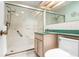 Bathroom featuring glass-enclosed shower, neutral tile, a toilet, and a green countertop at 417 Broadway, Dunedin, FL 34698