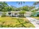 Charming single-story home featuring lush landscaping, mature trees, and a well-maintained front lawn at 417 Broadway, Dunedin, FL 34698