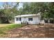 Charming single-story home with a white exterior, black shutters, a metal roof and inviting front yard at 4522 5Th St, Zephyrhills, FL 33542