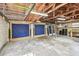 Large garage features exposed rafters, concrete walls and floor and two blue covered doors at 4560 7Th N Ave, St Petersburg, FL 33713