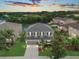 Stunning aerial view of a two-story home with lush greenery and a serene pond backdrop at sunset at 5804 Butterfield St, Riverview, FL 33578