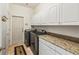 Well-lit laundry room featuring a granite countertop, cabinets, and stainless steel washer and dryer at 6038 Palomaglade Dr, Lithia, FL 33547