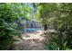 A serene backyard view with a stepping stone path leading to the inviting, screened-in pool area at 6110 N Suwanee Ave, Tampa, FL 33604