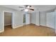 Bedroom featuring open bathroom entry, a ceiling fan, and neutral-colored walls and wood flooring at 6110 N Suwanee Ave, Tampa, FL 33604